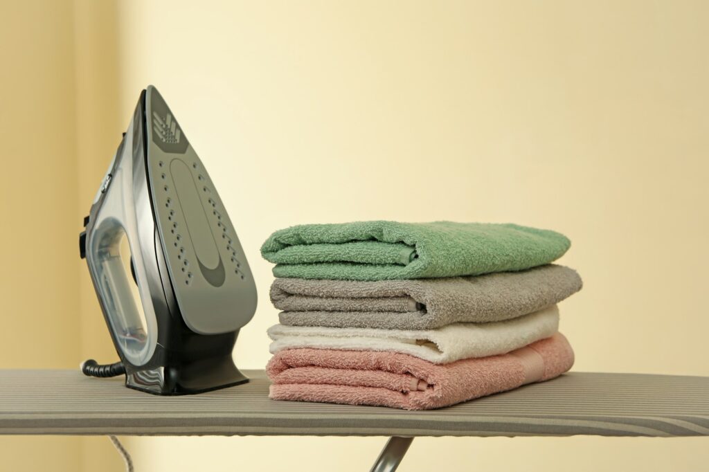 Ironing board with iron and pile of towels